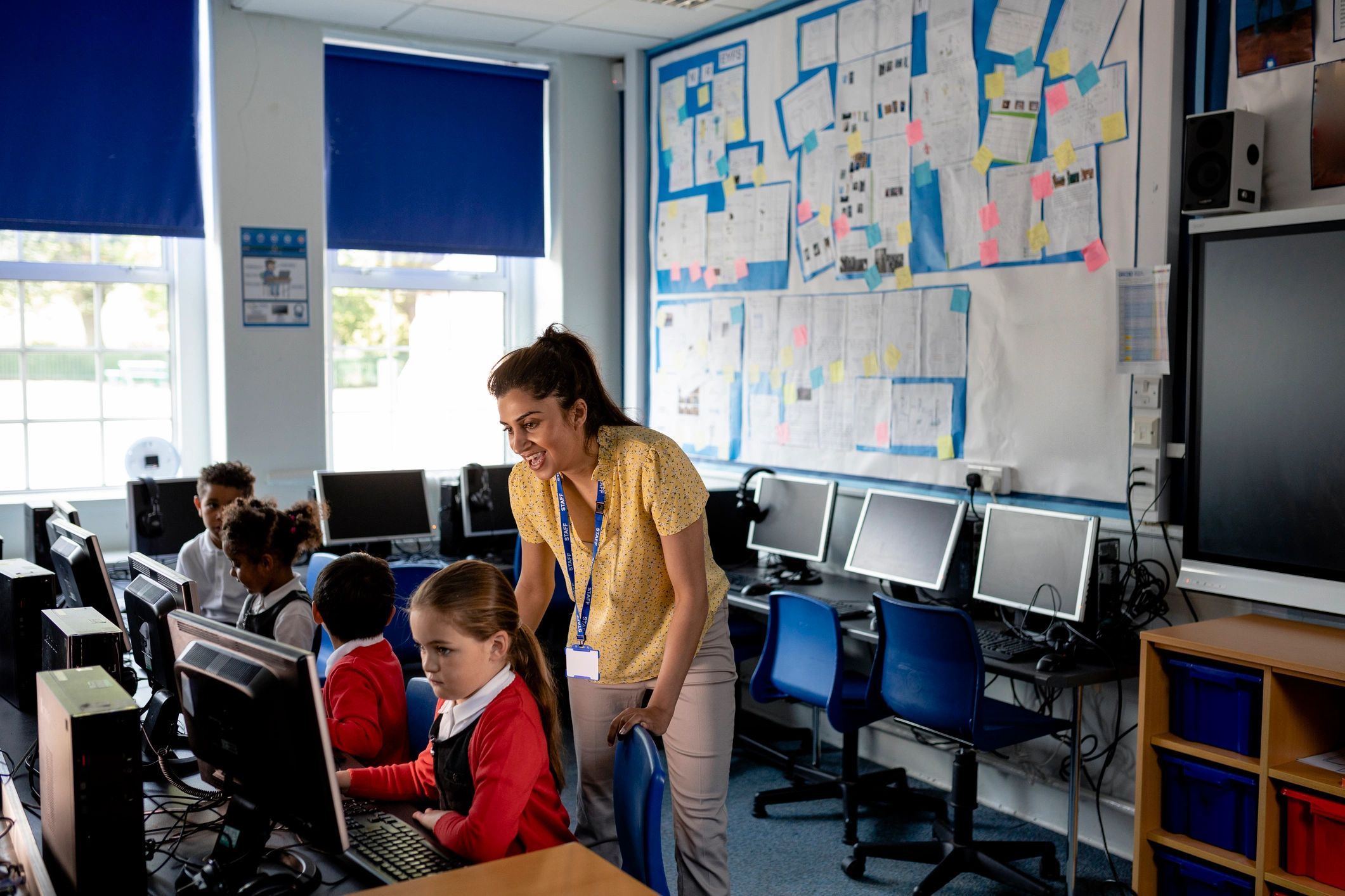 Teacher guiding children during a school computer class