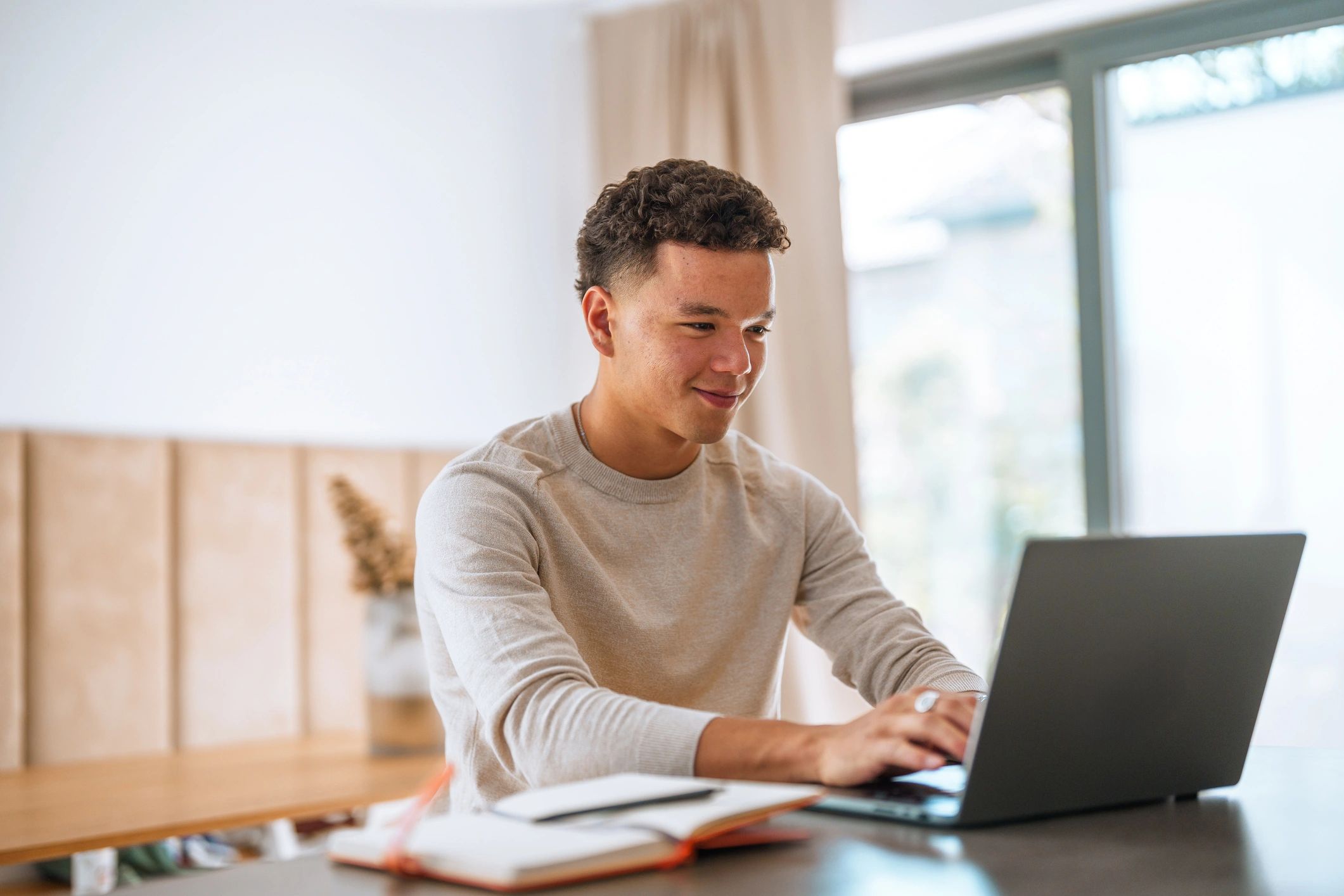 Jeune étudiant travaillant sur un ordinateur portable à la maison