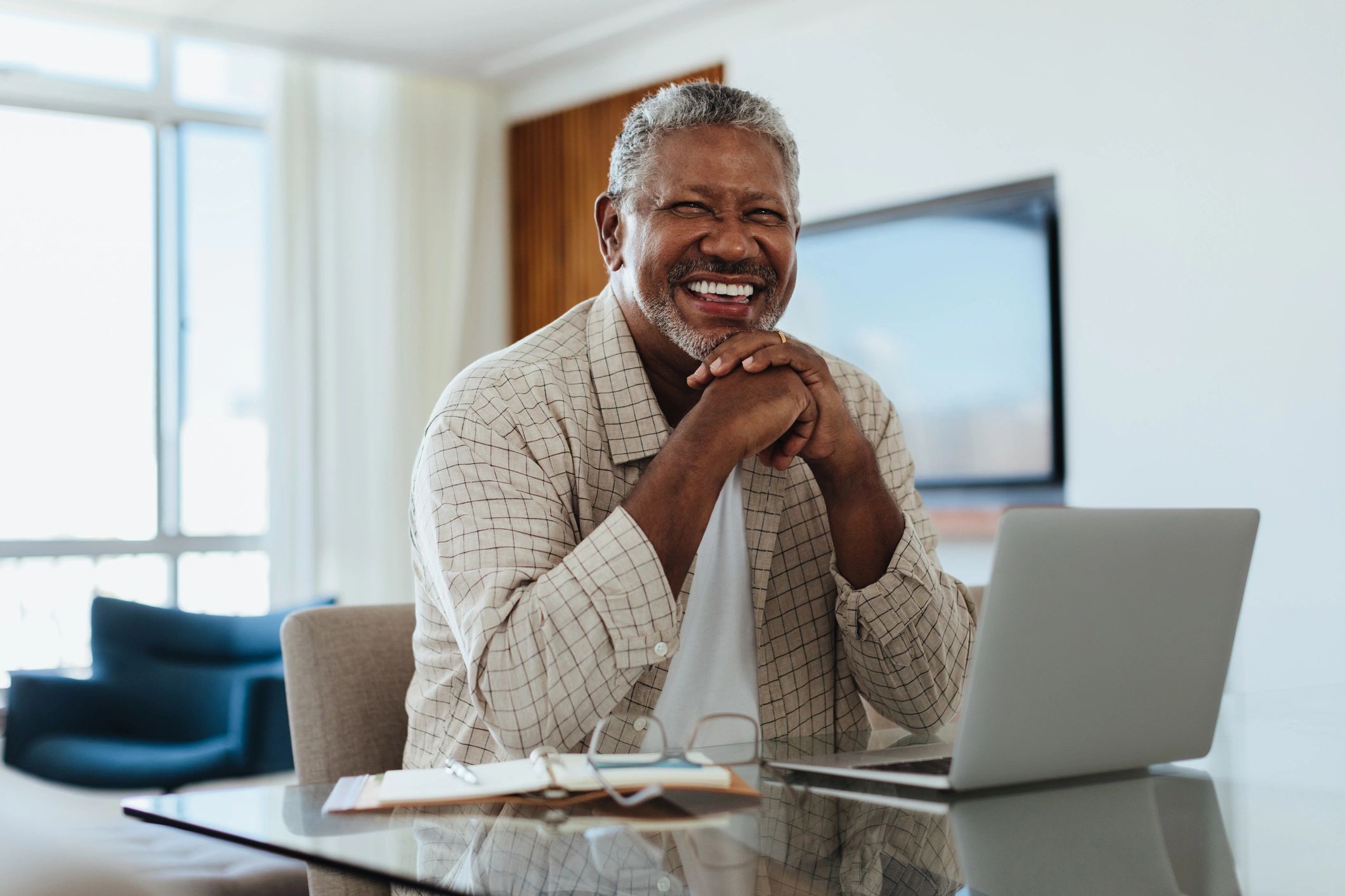 Cheerful senior man working on a laptop at home office