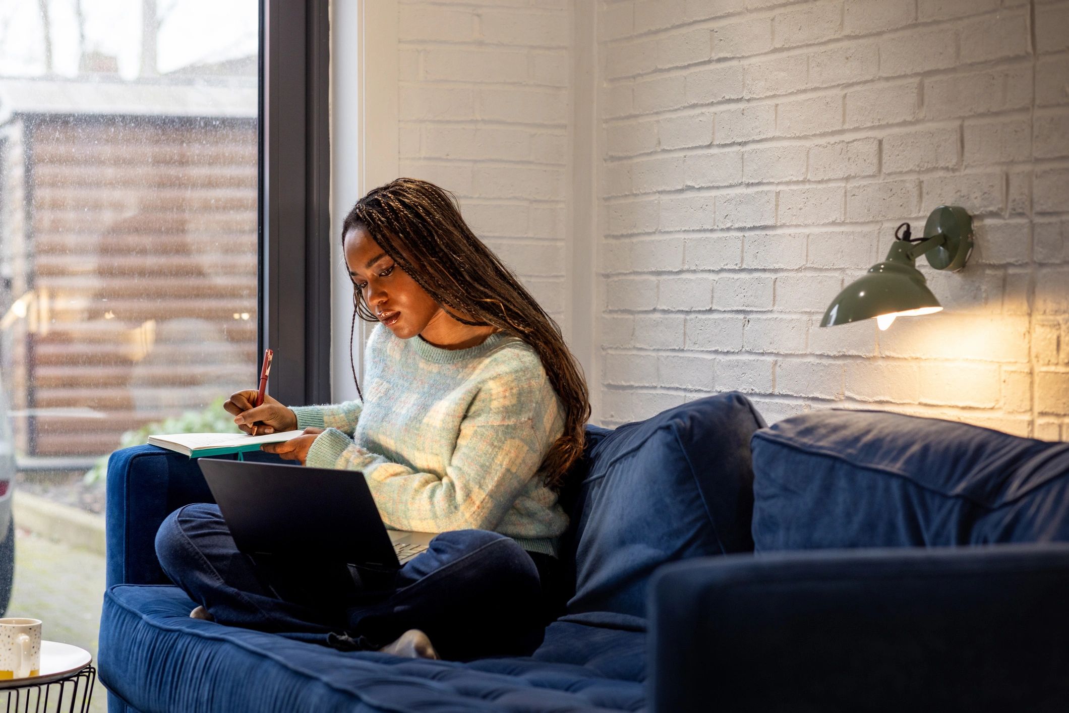 University student studying at home with a laptop and books