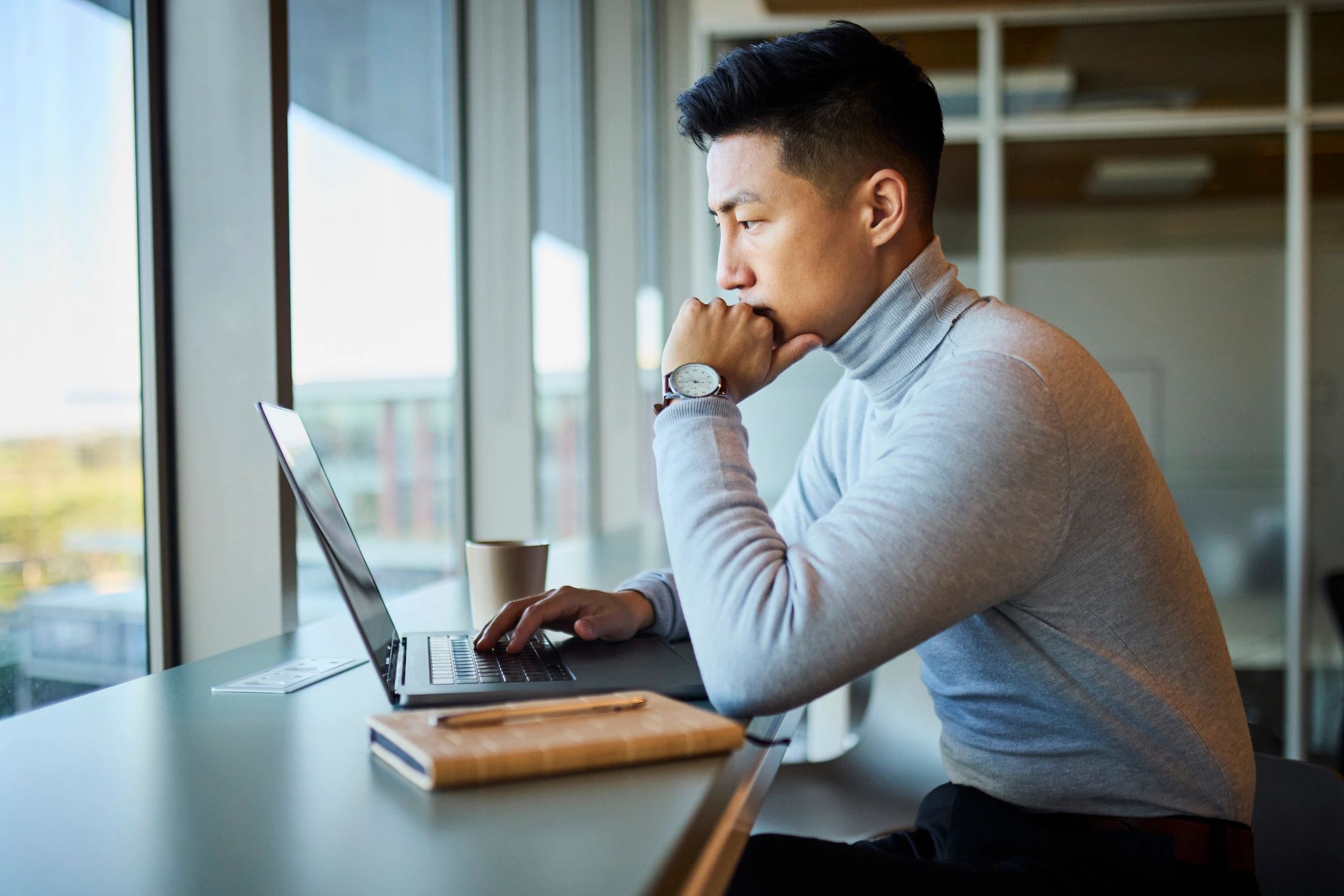 Professional working thoughtfully on a laptop in an office